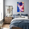 gold frame wall art painting depicts woman wearing round sunglasses and large hoop earrings