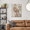 wall art canvas painting above the sofa depicts a woman wearing white flowers